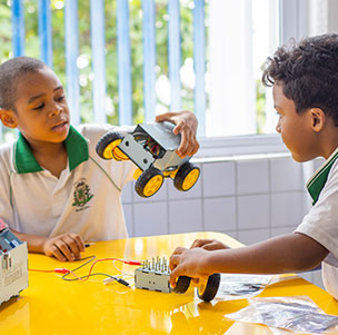 duas crianças montando uma casinha com peça de papelão